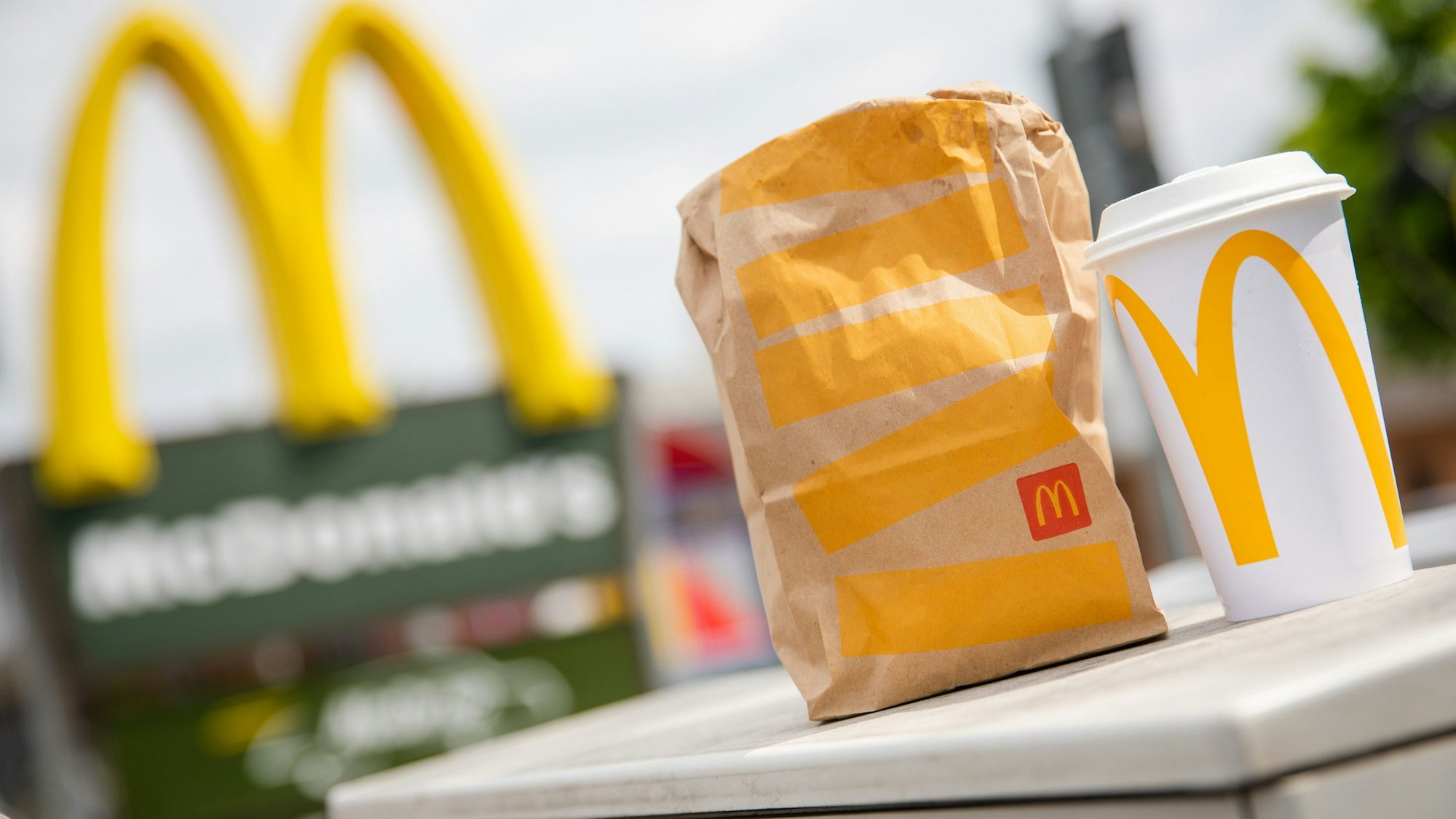 Eine McDonald's To-Go-Tüte und ein To-Go-Becher stehen vor einer McDonald's-Filiale (Symbolbild): Nach der zweiten Runde der Gespräche ruft die Gewerkschaft NGG zu Warnstreiks auf.