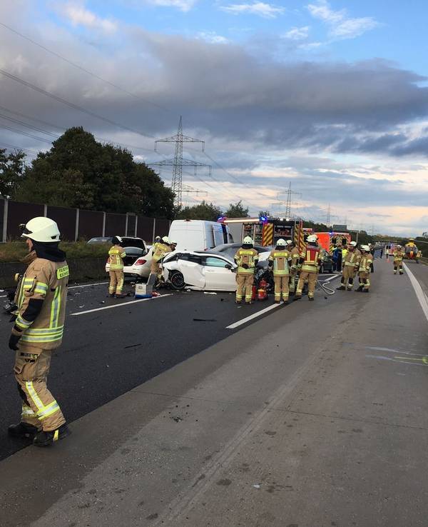 Zahlreiche Feuerwehrleute stehen auf der Autobahn an mehreren Autowracks, im Hintergrund ein Rettungshubschrauber.