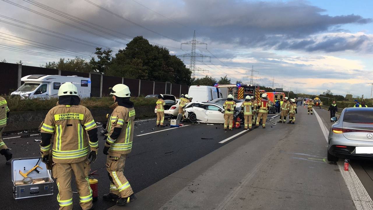 Zahlreiche Feuerwehrleute stehen auf der Autobahn an mehreren Autowracks, im Hintergrund ein Rettungshubschrauber.