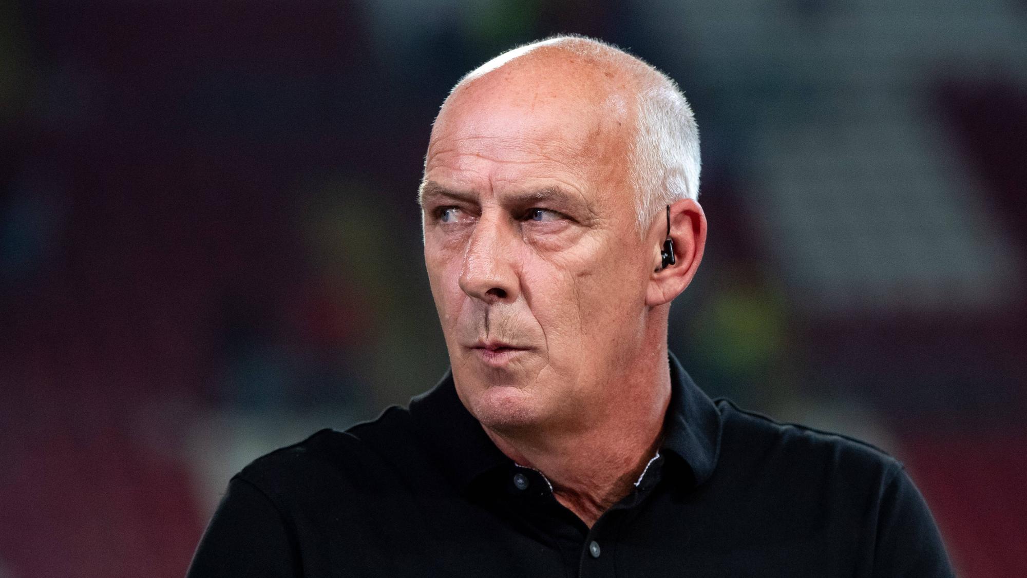 Mario Basler blickt sich finster um.
