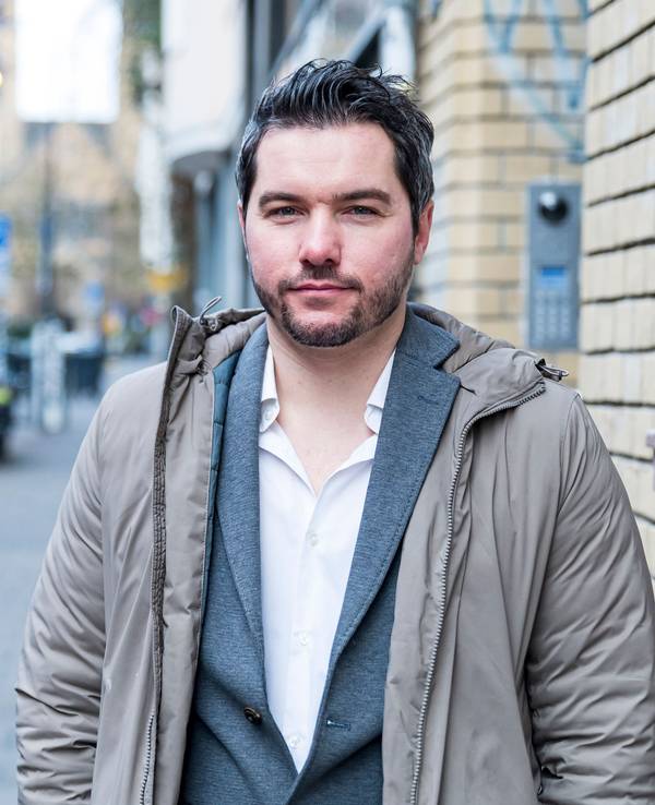 Stephan Hinz steht in lockeren Klamotten auf der Straße in Köln und schaut in die Kamera.