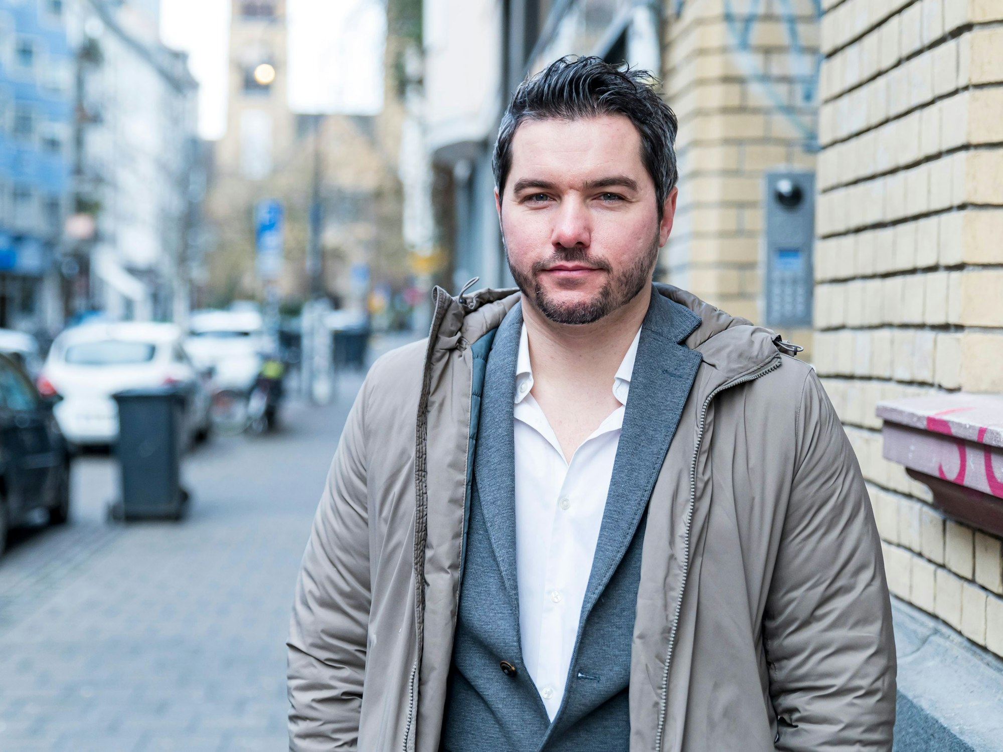 Stephan Hinz steht in lockeren Klamotten auf der Straße in Köln und schaut in die Kamera.