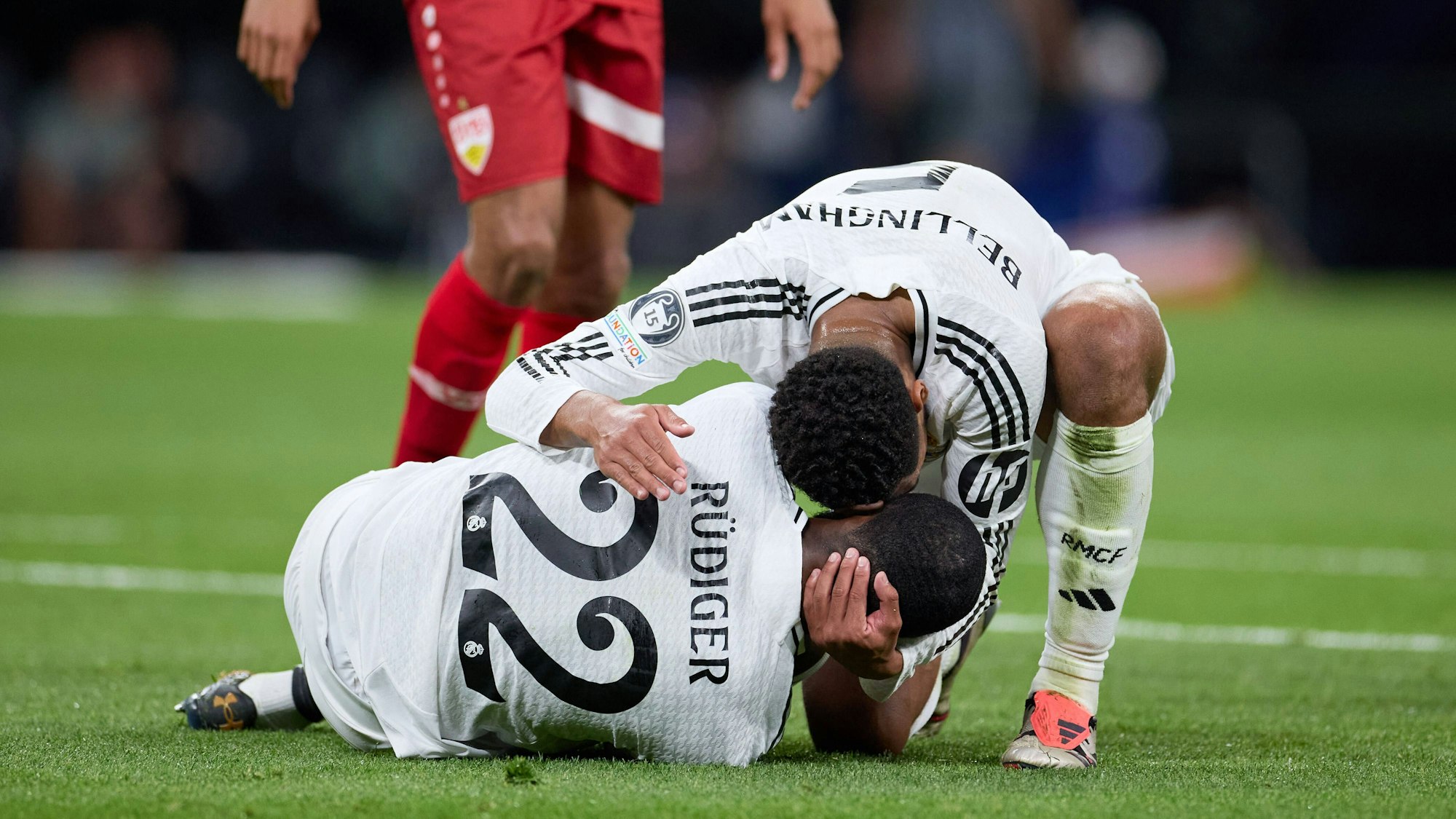 Antonio Rüdiger liegt im Spiel der Champions League zwischen Real Madrid und dem VfB Stuttgart am Boden, Jude Bellingham ist als Erster bei ihm.