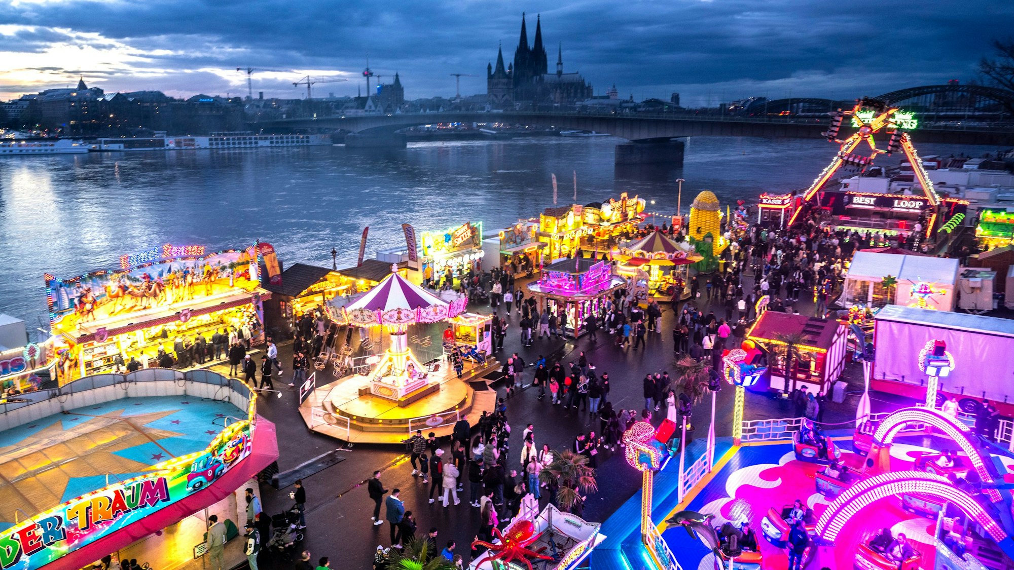 Die Deutzer Kirmes leuchtet in der Abenddämmerung.