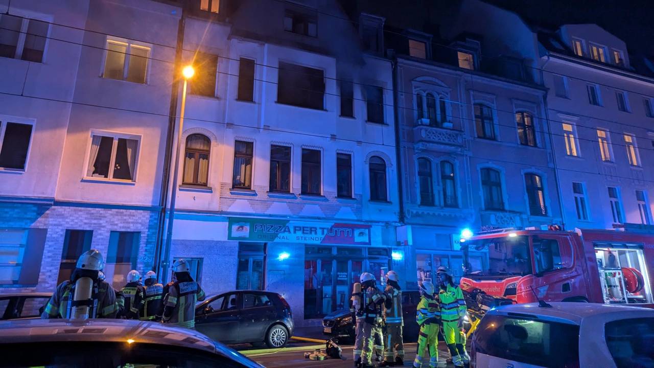Feuerwehr steht mit großen Wagen und vielen Einsatzkräften vor einem Gebäude auf der Zülpicher Straße in Köln.