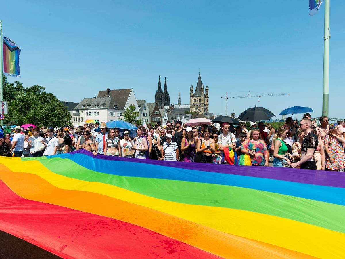 Menschen stehen hinter einer riesigen Regenbogenfahne.