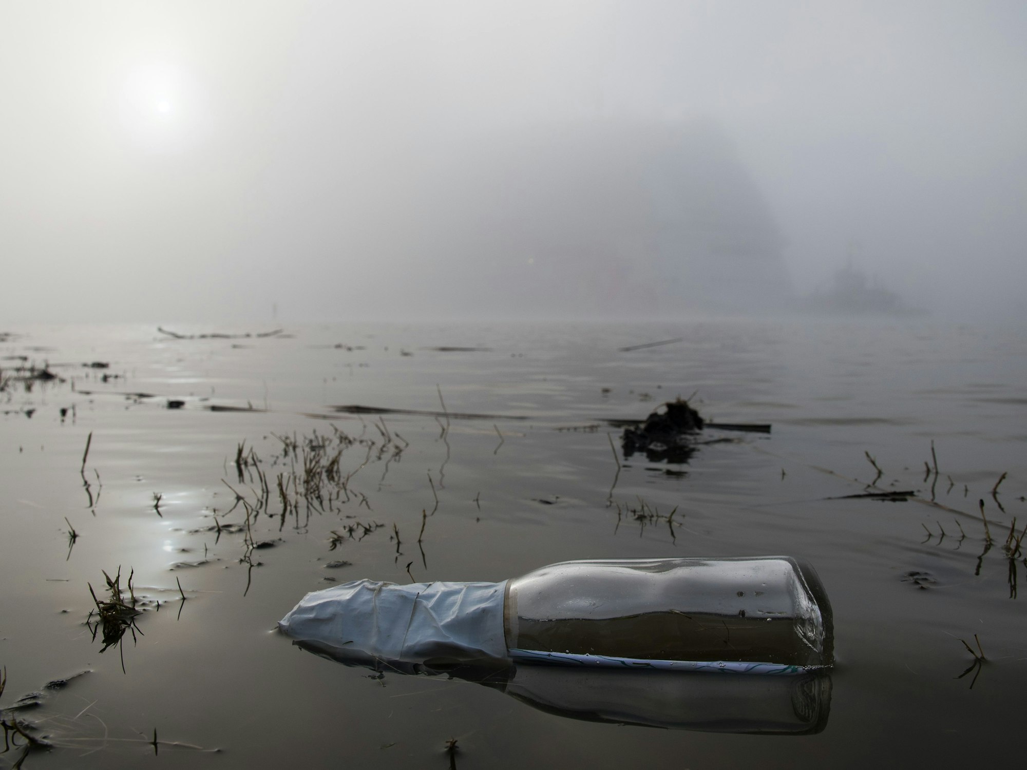 Im Vordergrund treibt eine Flaschenpost in der Ems.