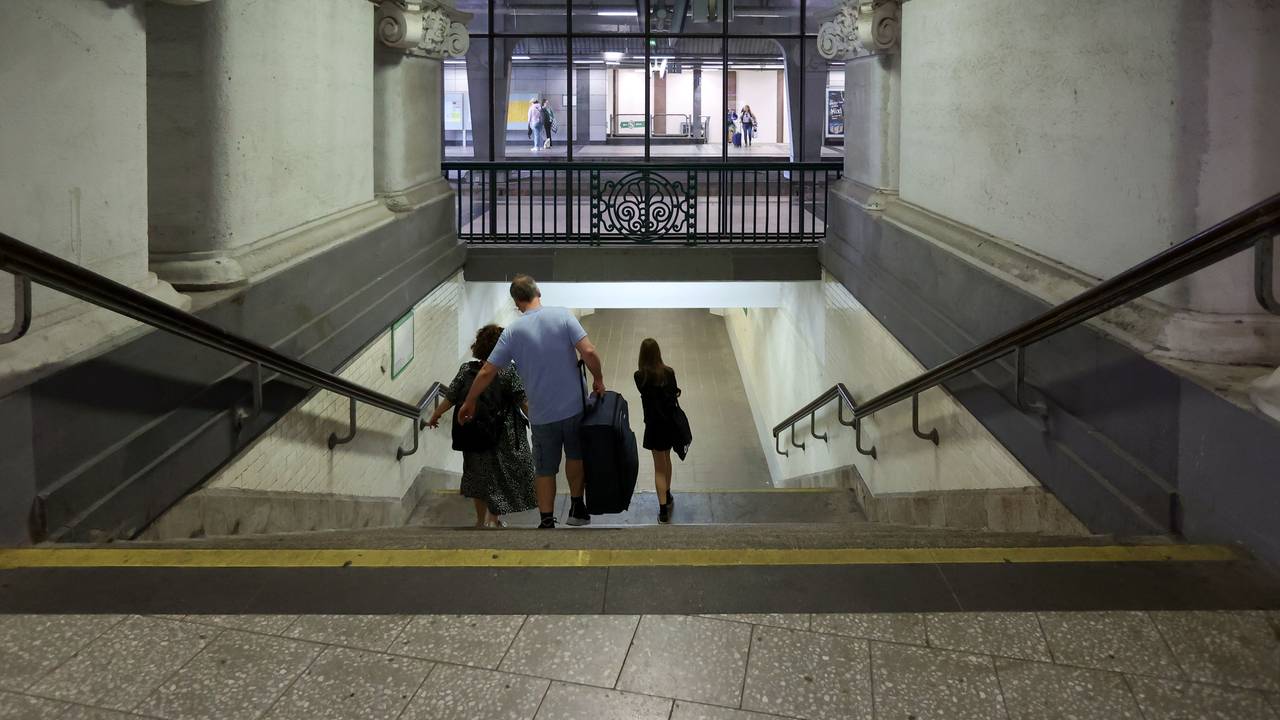 Drei Menschen gehen im Bahnhof Köln Messe/Deutz mit ihrem Gepäck eine Treppe herunter.