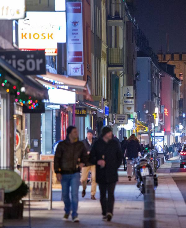 Fußgänger gehen und Autos fahren in der Dunkelheit über die Severinstraße in Köln.
