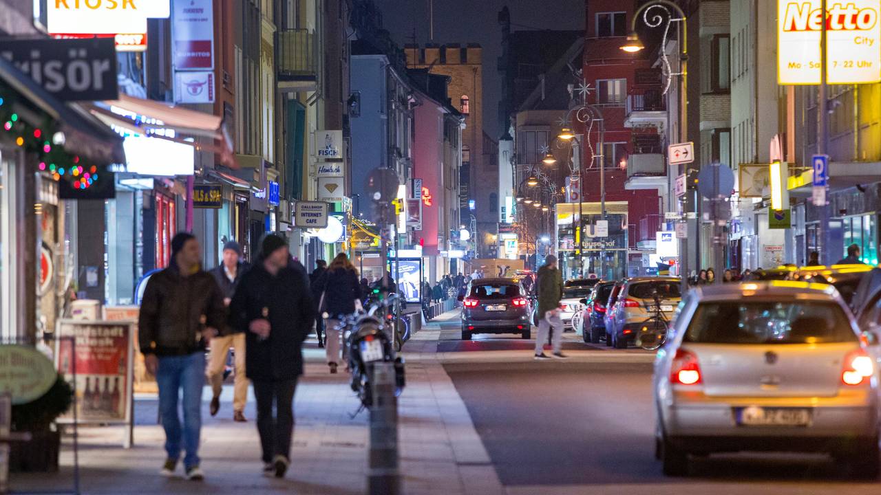 Fußgänger gehen und Autos fahren in der Dunkelheit über die Severinstraße in Köln.