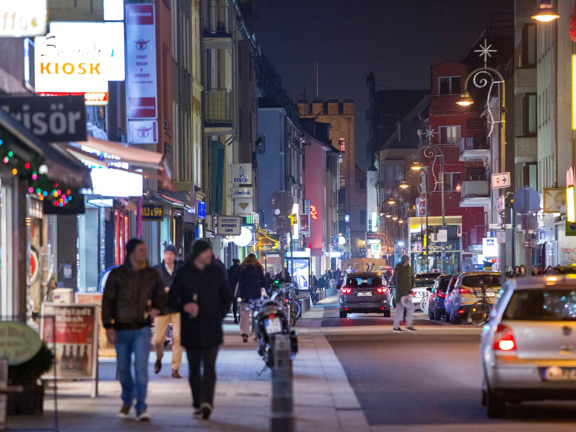 Fußgänger gehen und Autos fahren in der Dunkelheit über die Severinstraße in Köln.
