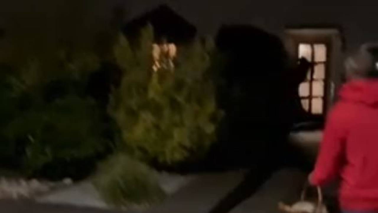 Mann in dunkler Kleidung sprintet durch ein Wohngebiet und wird von Anwohnenden gefilmt.