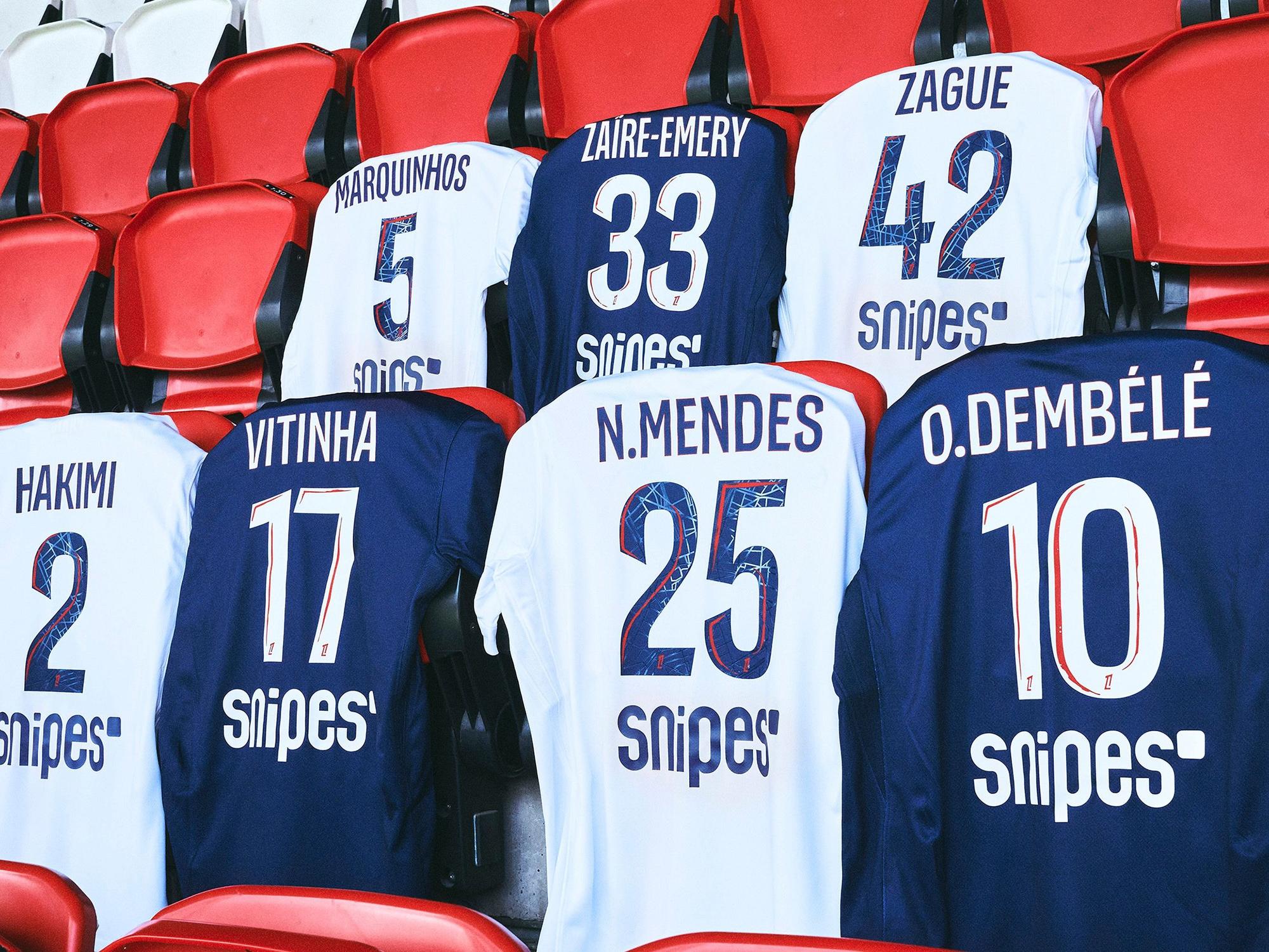 Mehrere Trikots von Paris St. Germain hängen auf einer Tribüne.