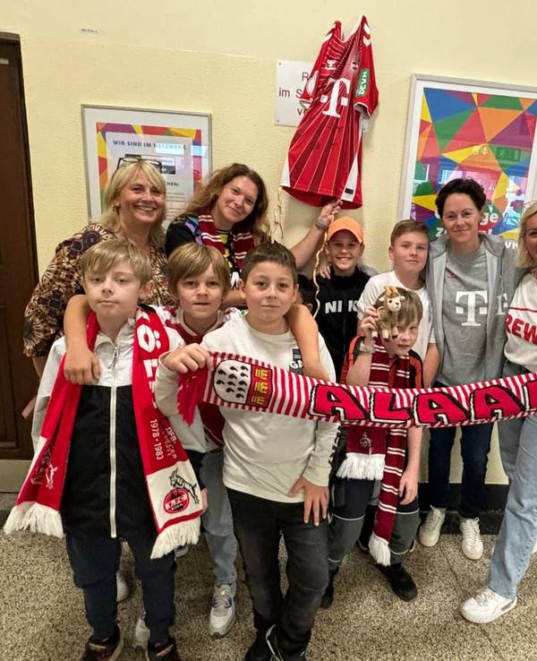 Einige Frauen und einige Kinder stehen in Kleidung des 1. FC Köln für ein Gruppenbild zusammen.