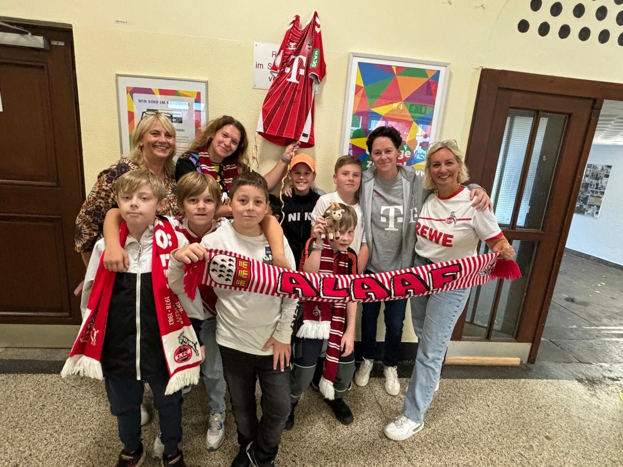 Einige Frauen und einige Kinder stehen in Kleidung des 1. FC Köln für ein Gruppenbild zusammen.