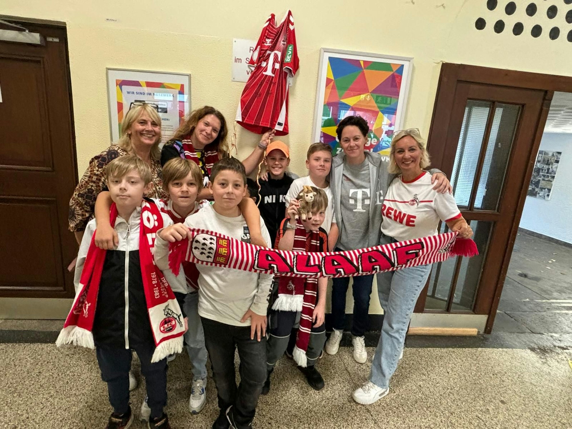Einige Frauen und einige Kinder stehen in Kleidung des 1. FC Köln für ein Gruppenbild zusammen.