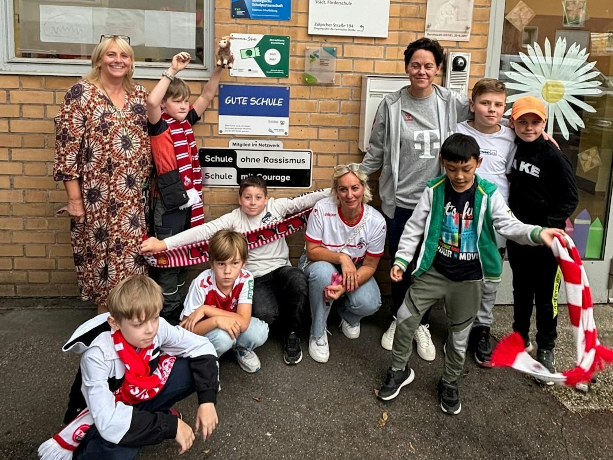 Drei Frauen und einige Kinder auf einem Gruppenbild vor einem Schulgebäude.