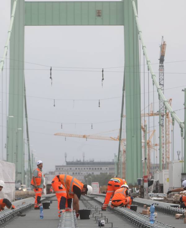 Bauarbeiter verlegen Gleise auf einer Brücke.