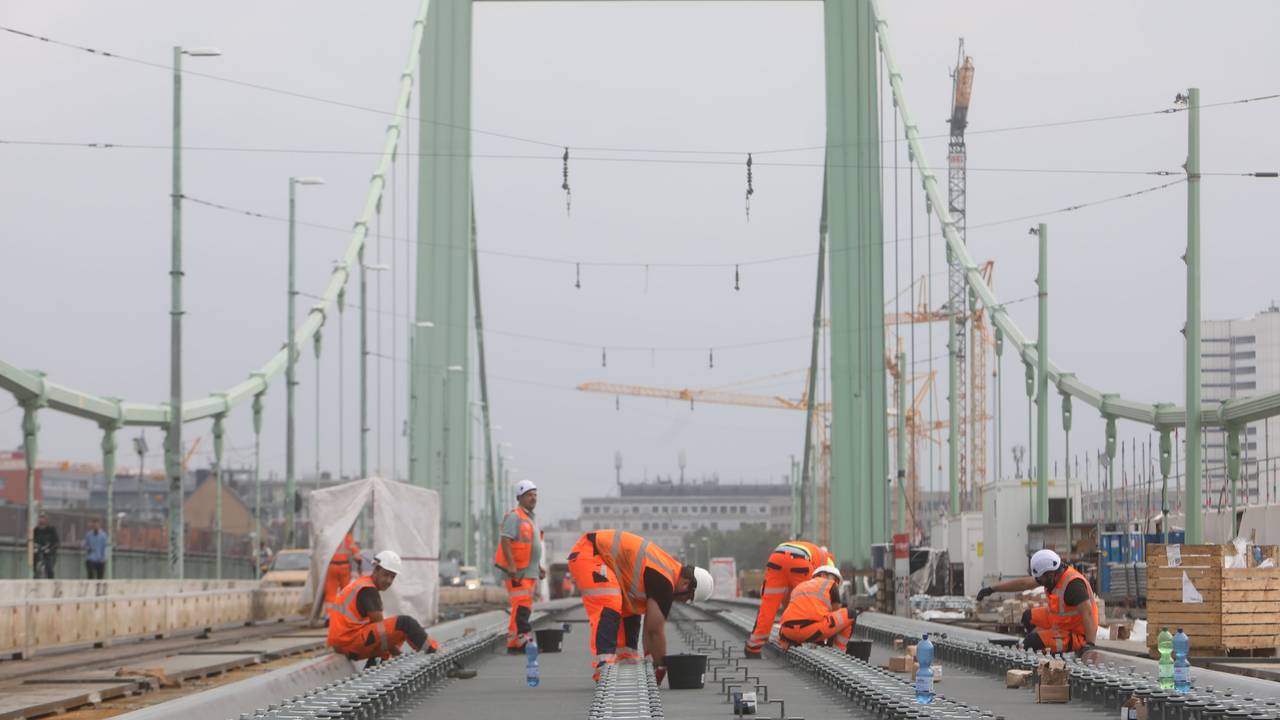 Bauarbeiter verlegen Gleise auf einer Brücke.