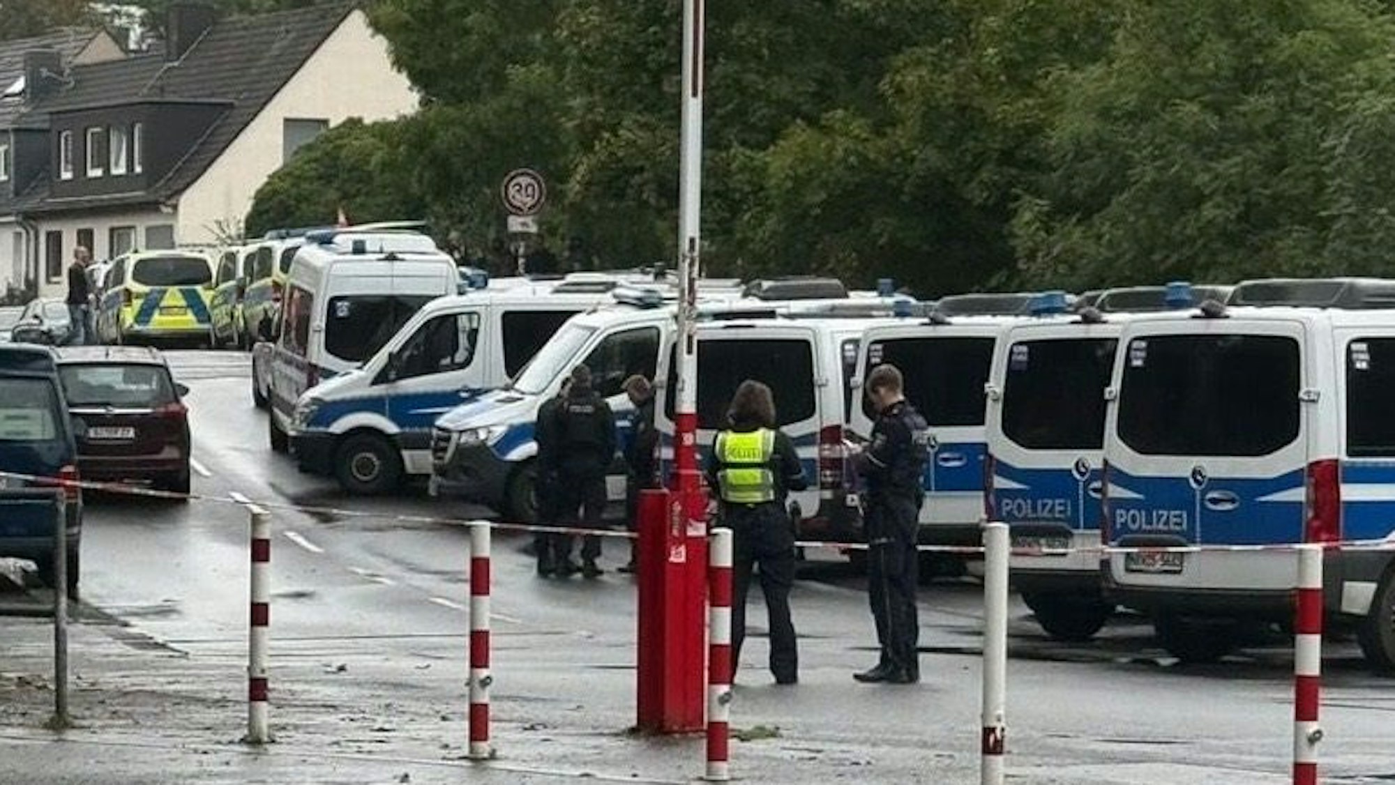 Einsatzkräfte stehen vor einer langen Reihe geparkter Polizeifahrzeuge.