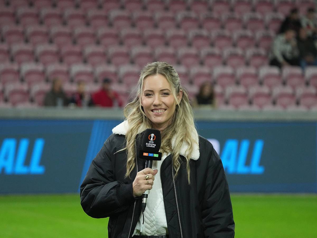 Laura Papendick steht auf dem Platz, hat ein Mikrofon in der Hand und lächelt in die Kamera.