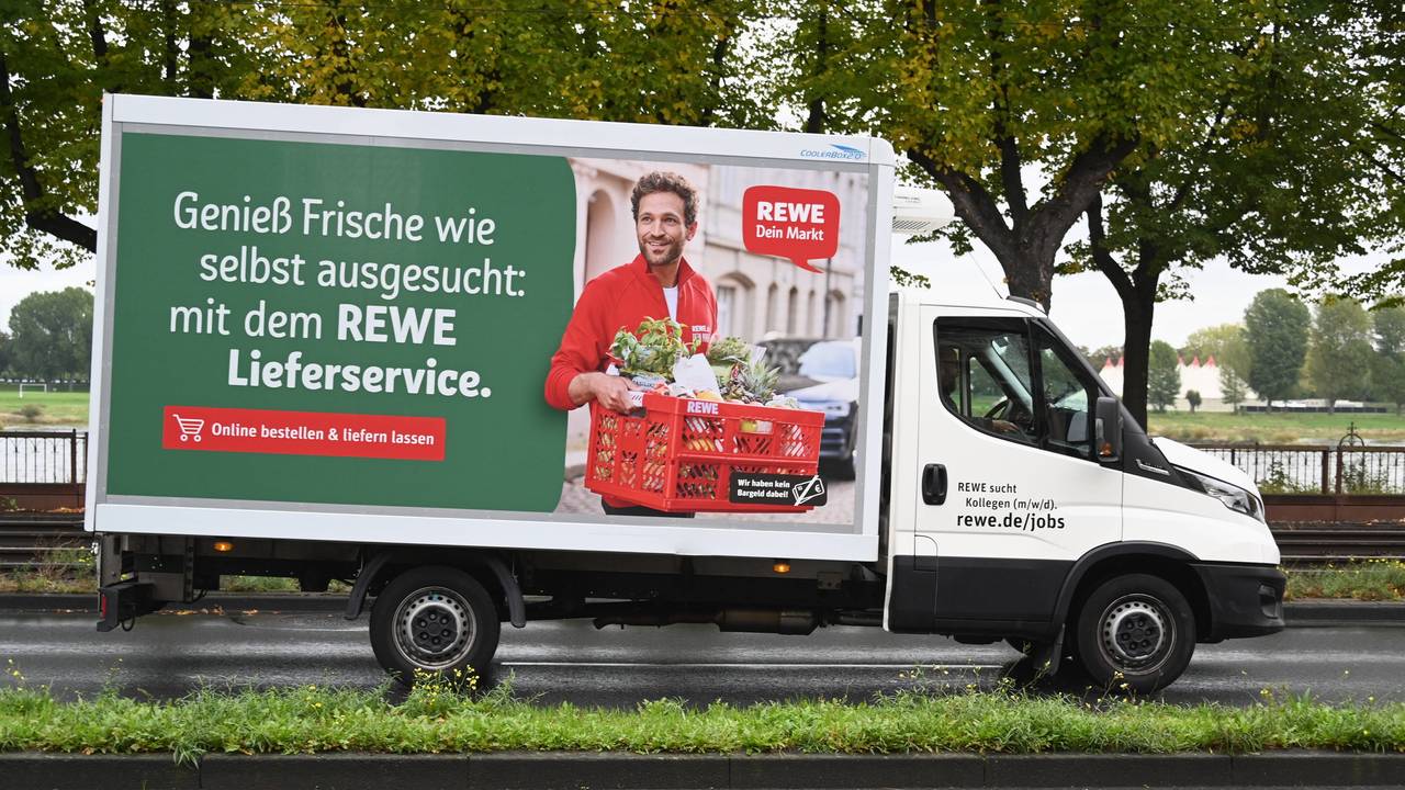 Ein Fahrzeug des Rewe Lieferservice fährt auf einer Straße.
