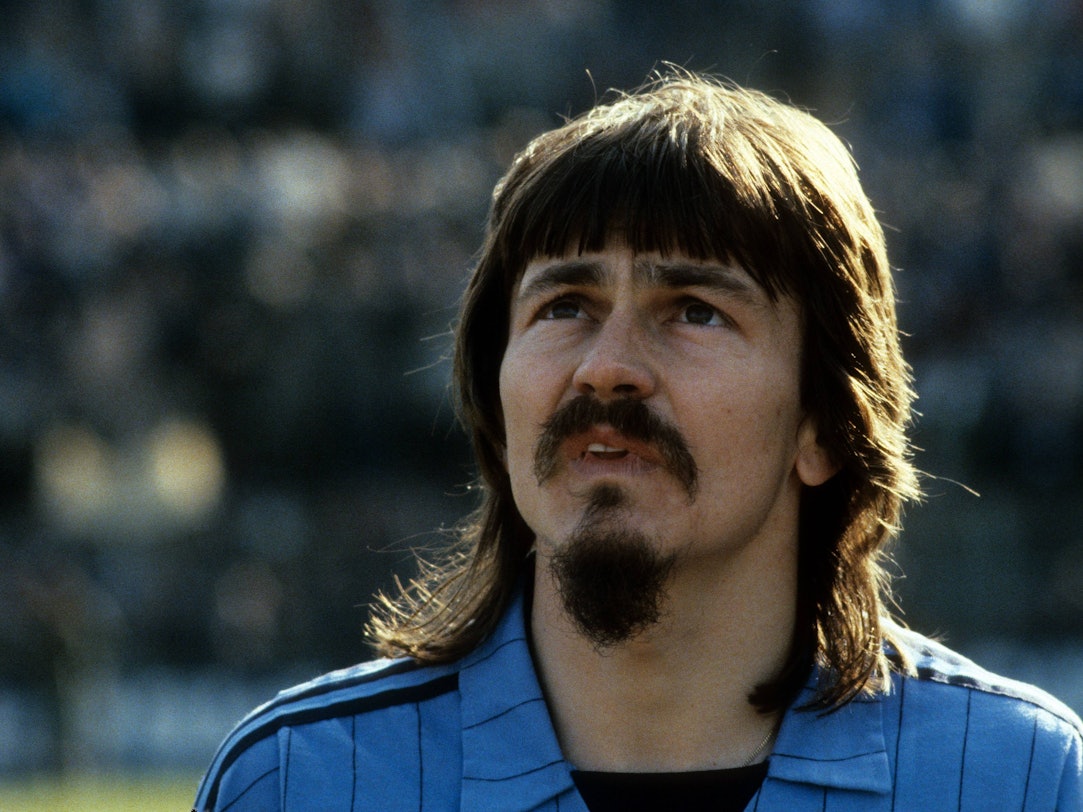 Ewald Lienen mit Vokuhila, Schnäuzer und Kinnbart.