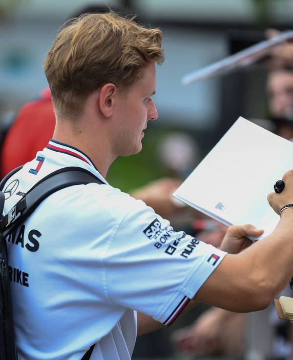 Mick Schumacher schreibt Autogramme.