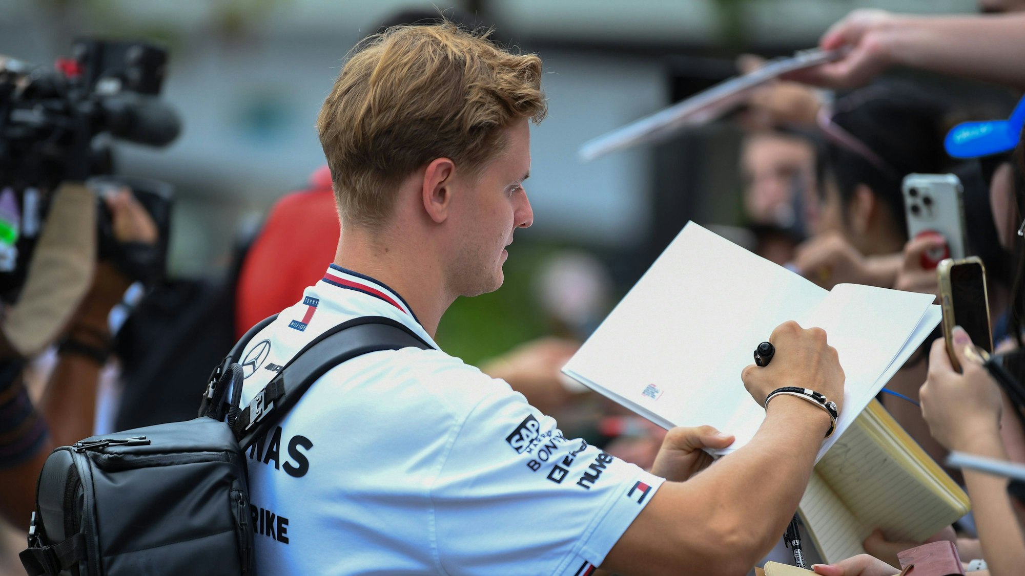 Mick Schumacher schreibt Autogramme.