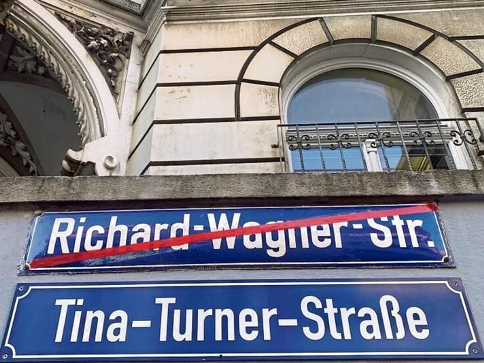 Zwei Straßenschilder hängen an einer Wand.