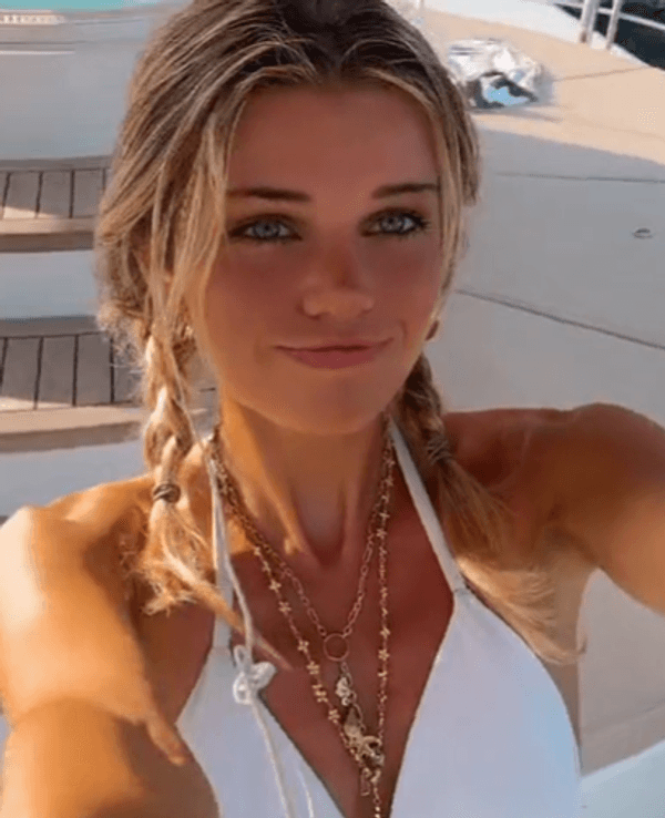 Estelle Ogilvy lächelt für ein Selfie-Video im weißen Bikini in die Kamera.
