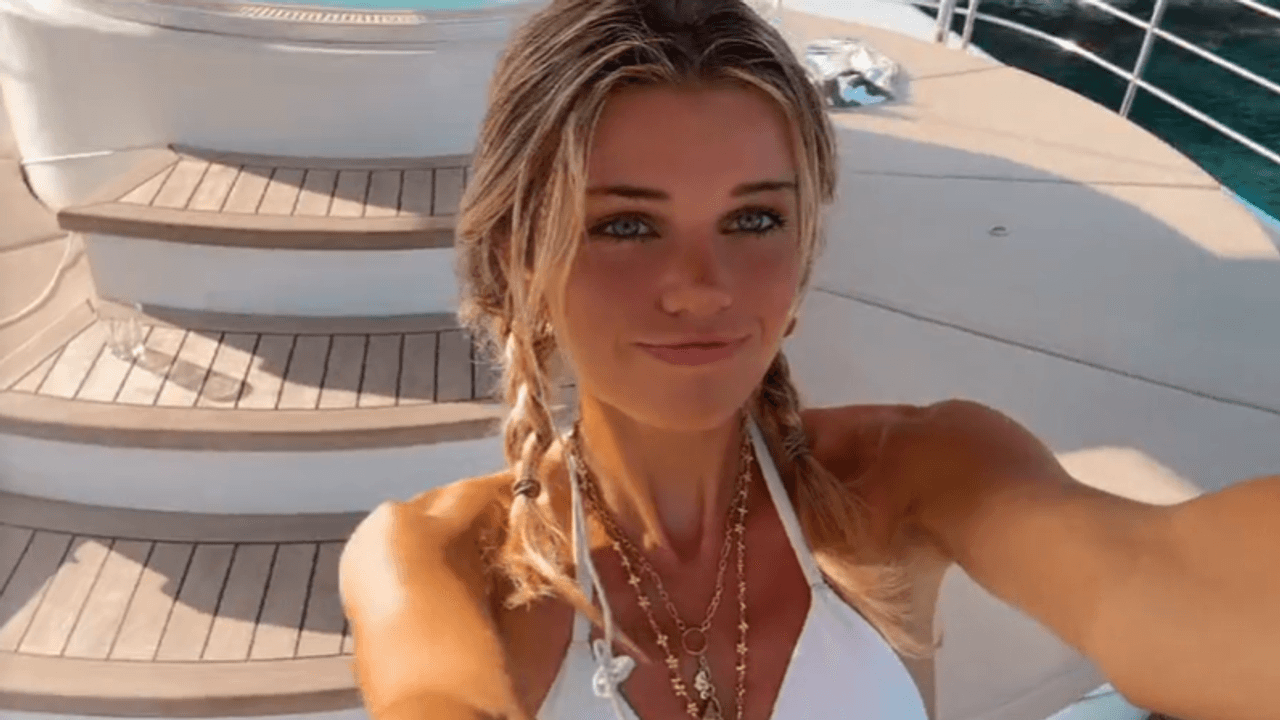 Estelle Ogilvy lächelt für ein Selfie-Video im weißen Bikini in die Kamera.