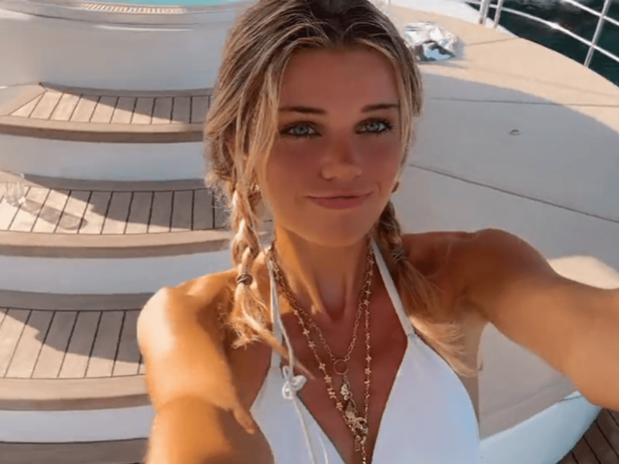 Estelle Ogilvy lächelt für ein Selfie-Video im weißen Bikini in die Kamera.