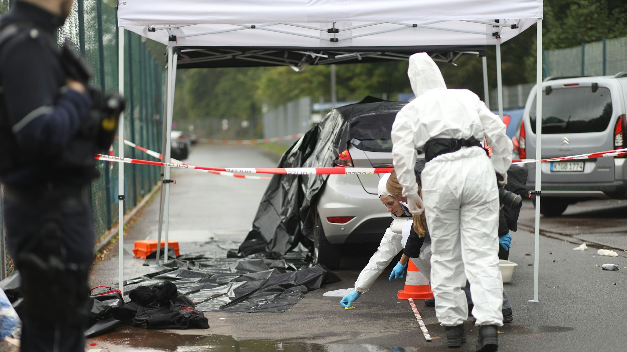 Die Polizei hat den Bereich um ein Auto abgesperrt, zwei Einsatzkräfte der Spurensicherung sind vor Ort.