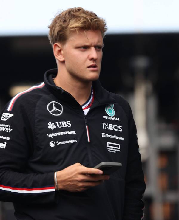 Mick Schumacher im Fahrerlager mit Handy in der Hand.