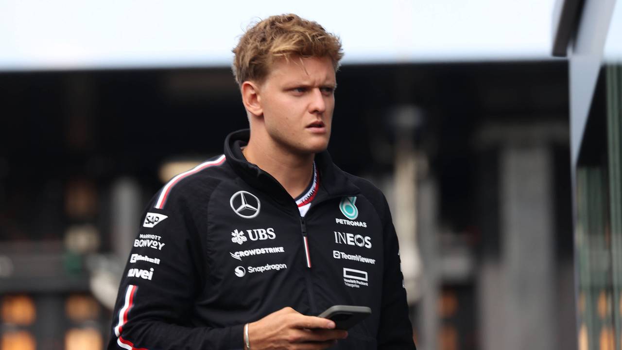 Mick Schumacher im Fahrerlager mit Handy in der Hand.