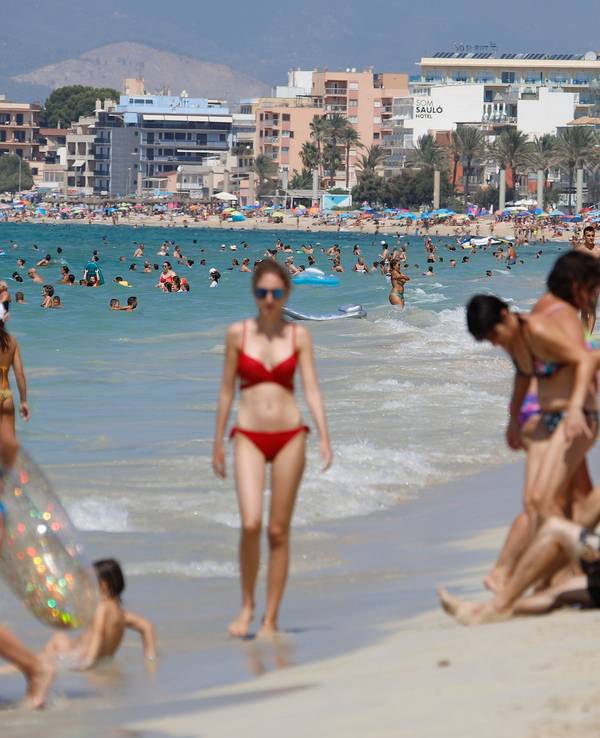 Menschen sonnen sich und schwimmen am Strand von Arenal auf Mallorca.