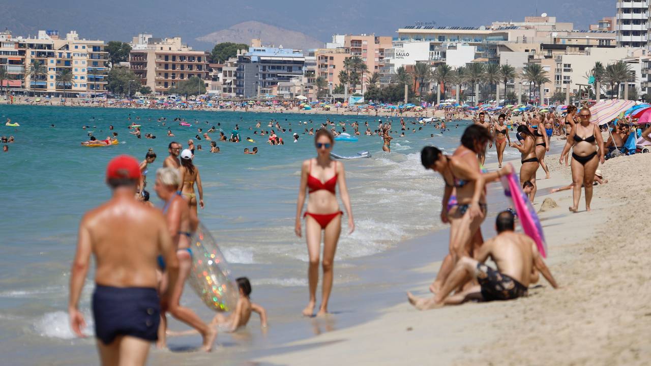 Menschen sonnen sich und schwimmen am Strand von Arenal auf Mallorca.
