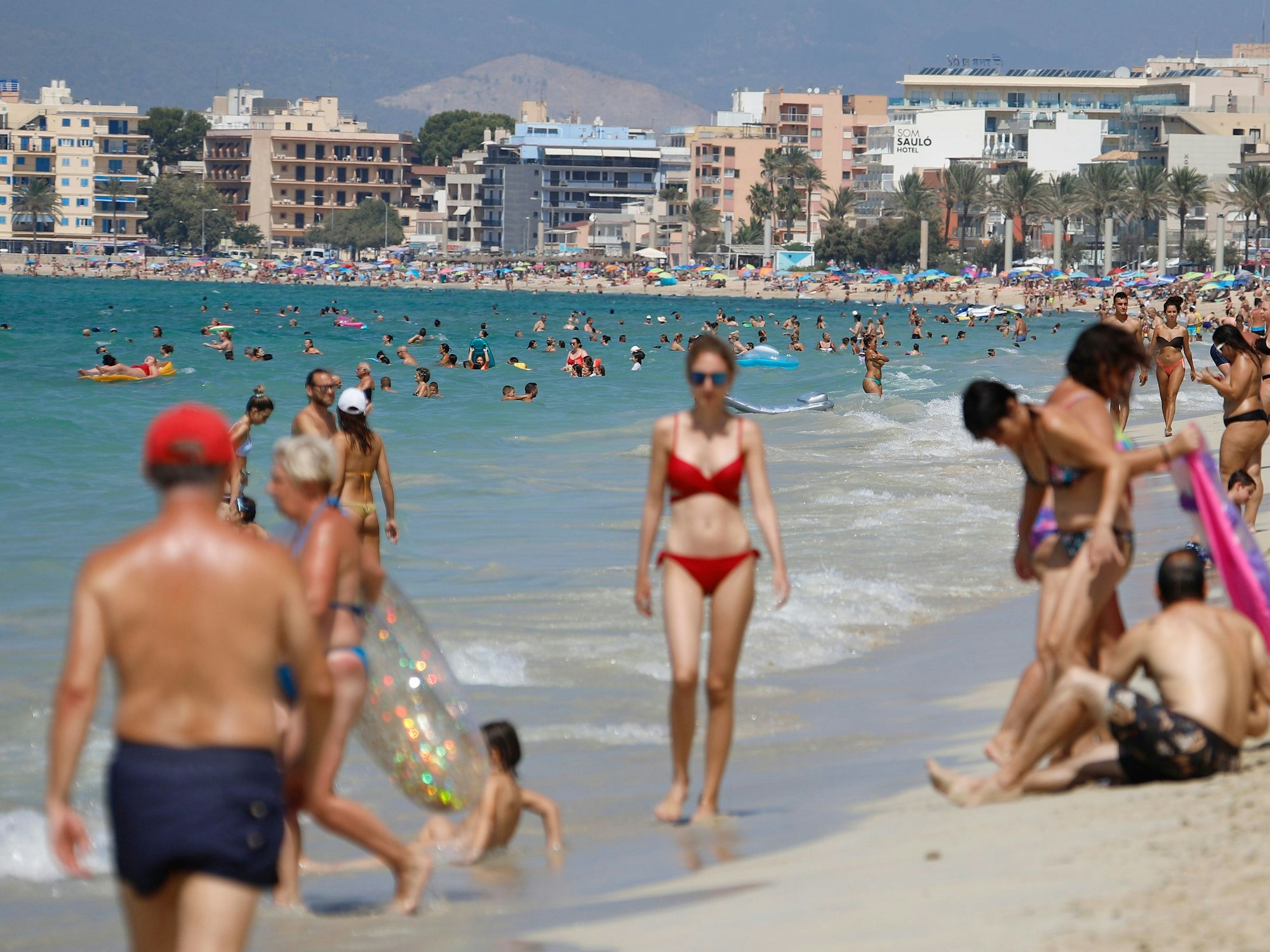 Menschen sonnen sich und schwimmen am Strand von Arenal auf Mallorca.