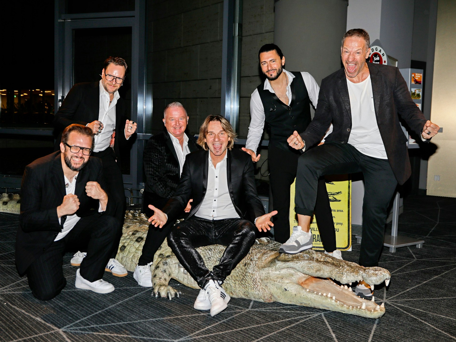 Die Höhner posieren auf einem Krokodil.