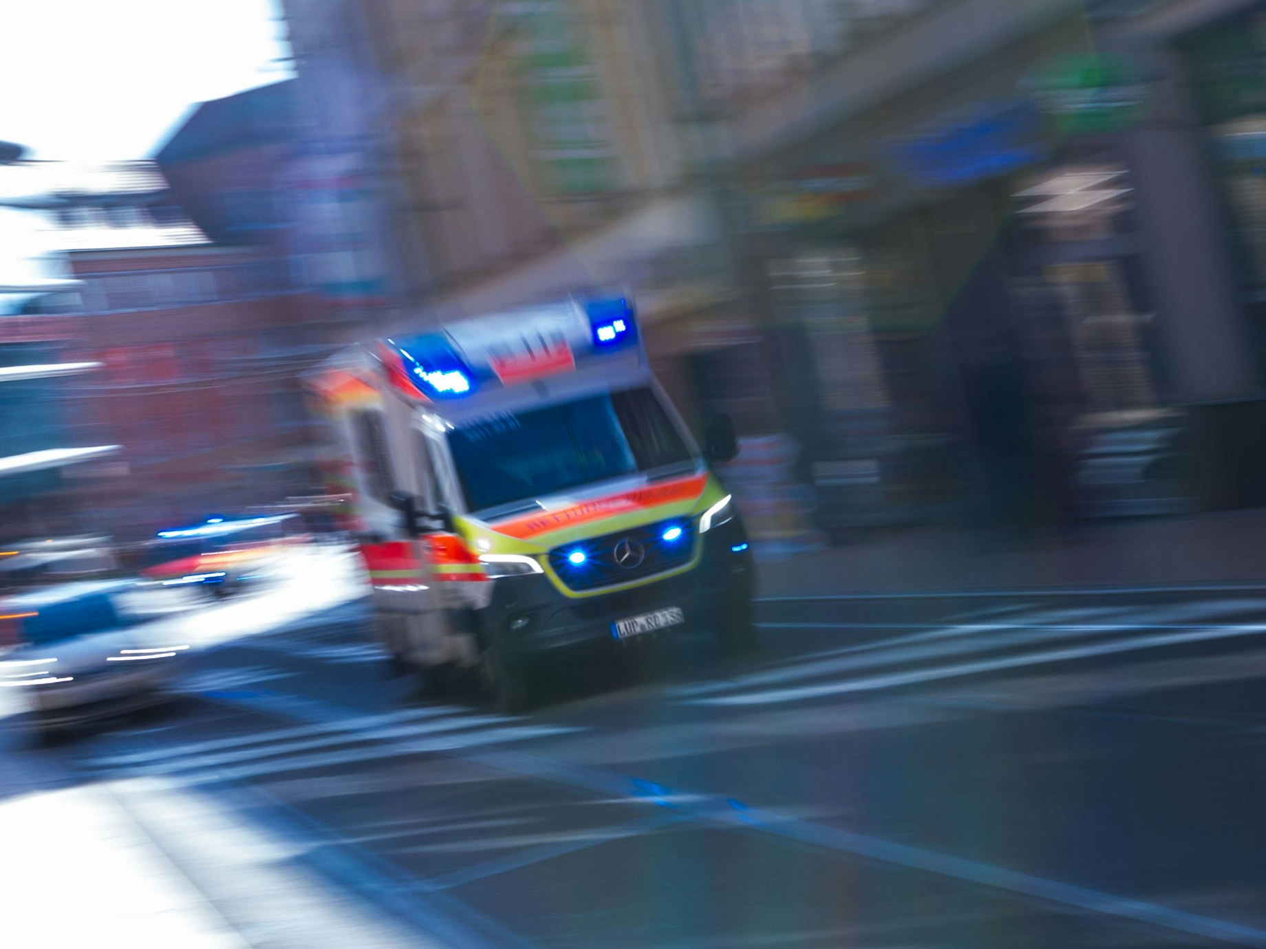 Ein Rettungsfahrzeug ist mit Blaulicht auf einer Straße unterwegs.