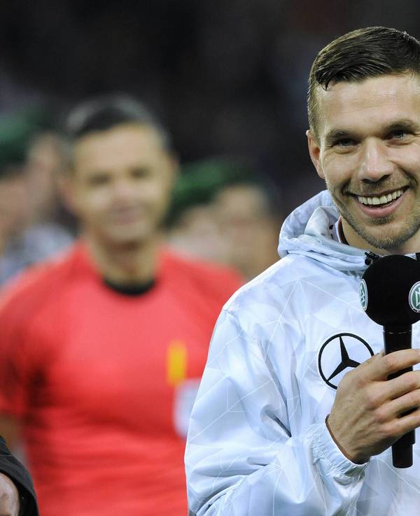 Lukas Podolski lacht mit Mikro in der Hand bei seinem DFB-Abschiedsspiel.