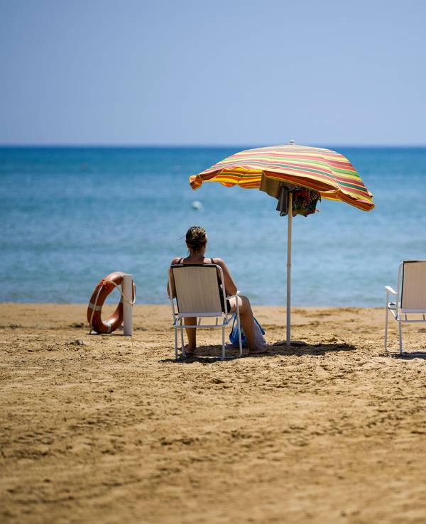 Eine Frau und ein Mann sitzen an einem Strand und schauen auf das Meer.