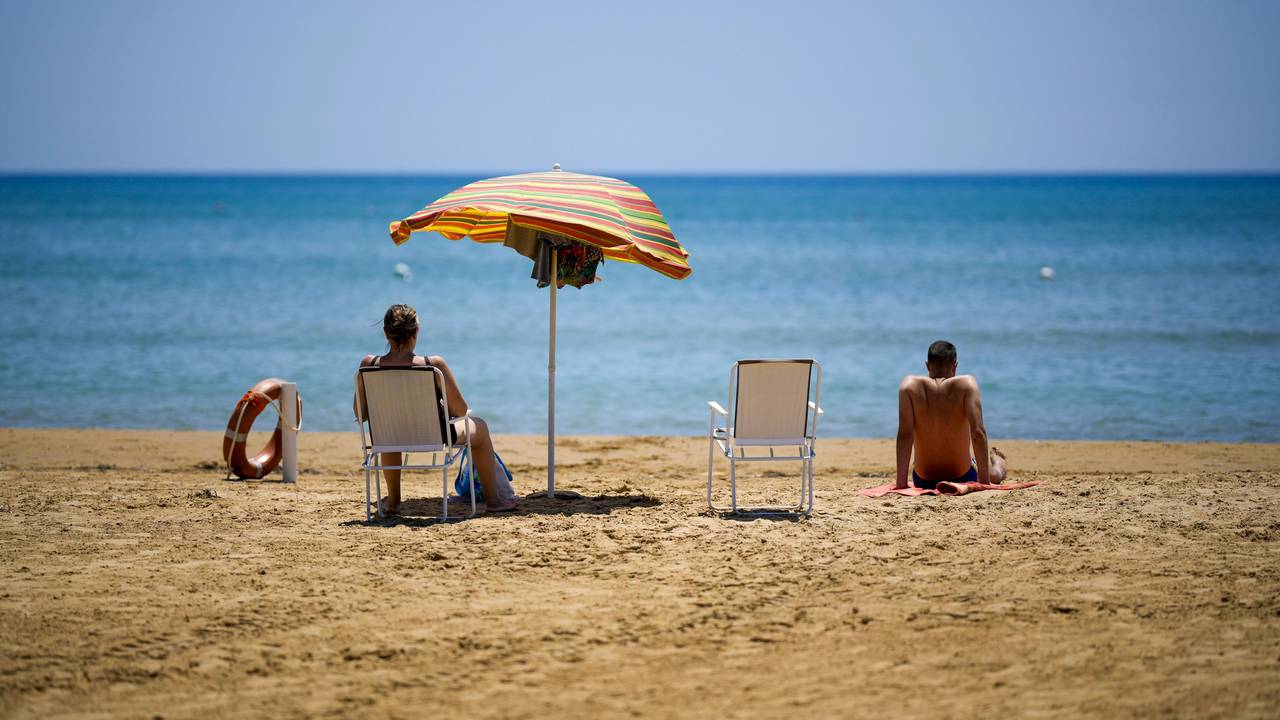 Eine Frau und ein Mann sitzen an einem Strand und schauen auf das Meer.