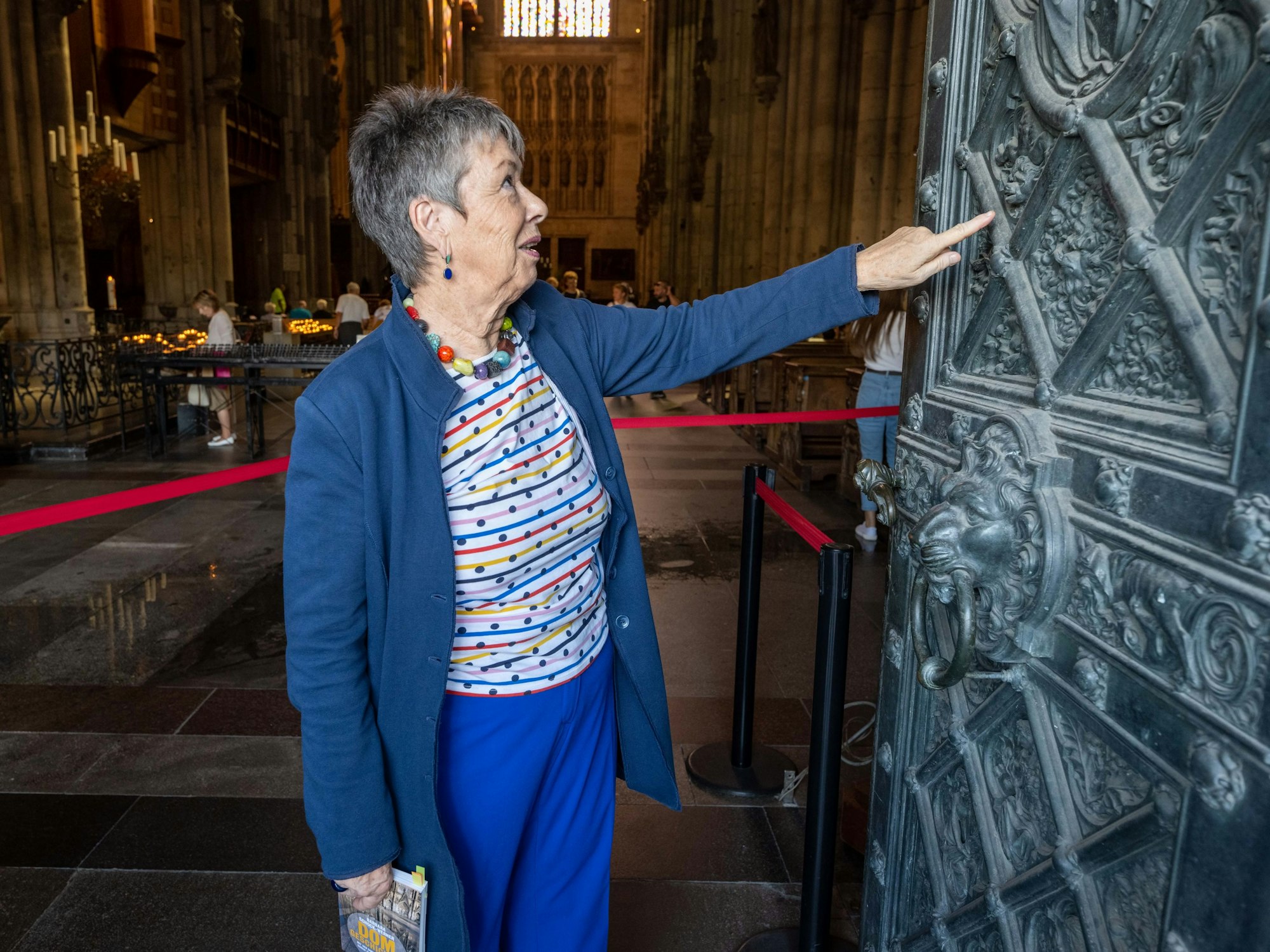 Barbara Schock-Werner fasst an eine offene Seitentür des Kölner Doms und betrachtet die Kunstwerke.