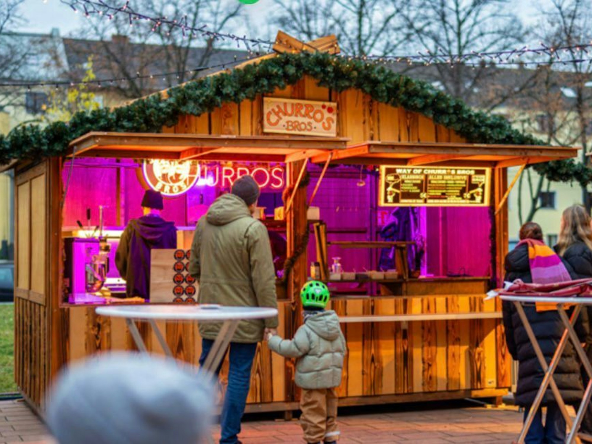 Gäste stehen vor einer Hütte am Sülzer Weihnachtsdorf.