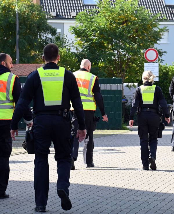 Mitarbeiter des Ordnungsamtes laufen über eine Straße.