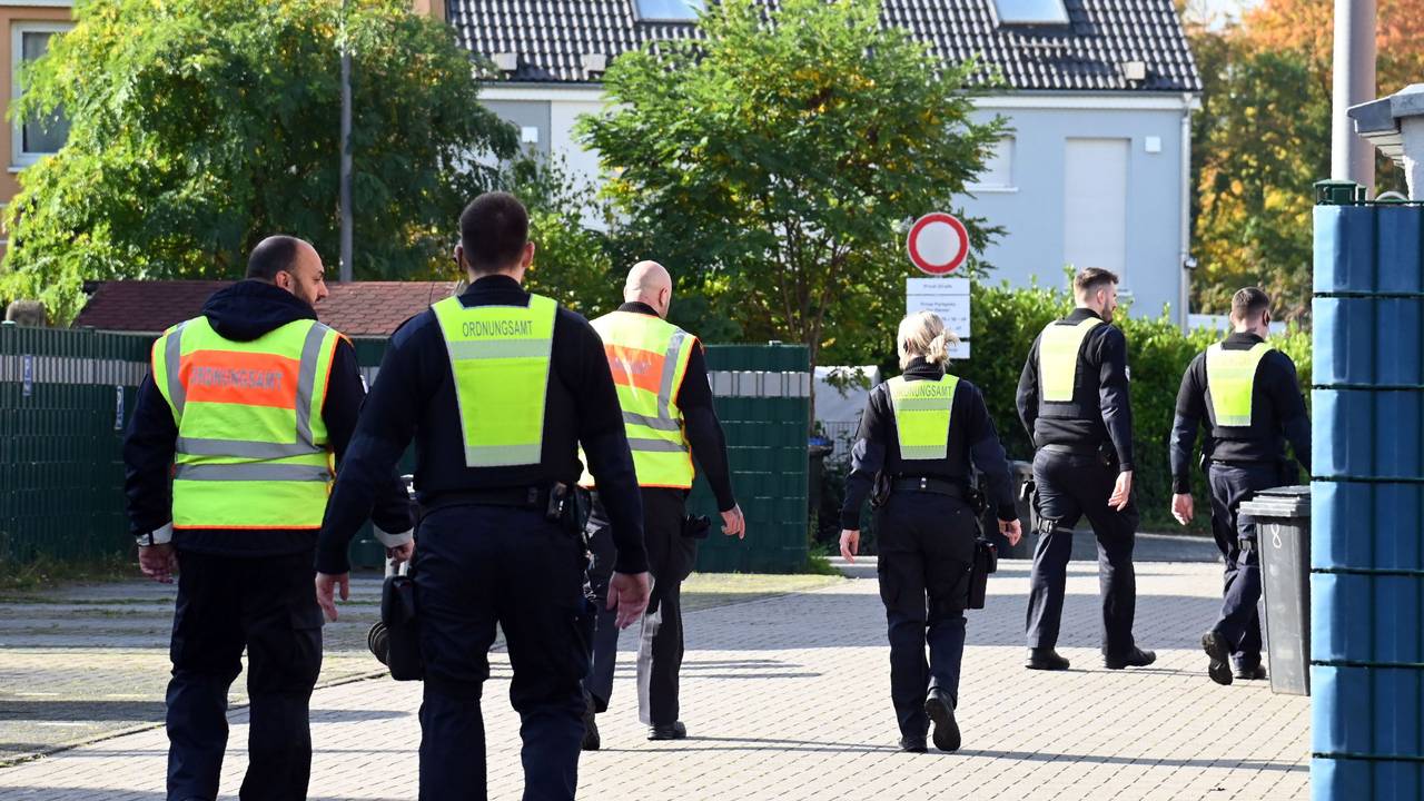 Mitarbeiter des Ordnungsamtes laufen über eine Straße.