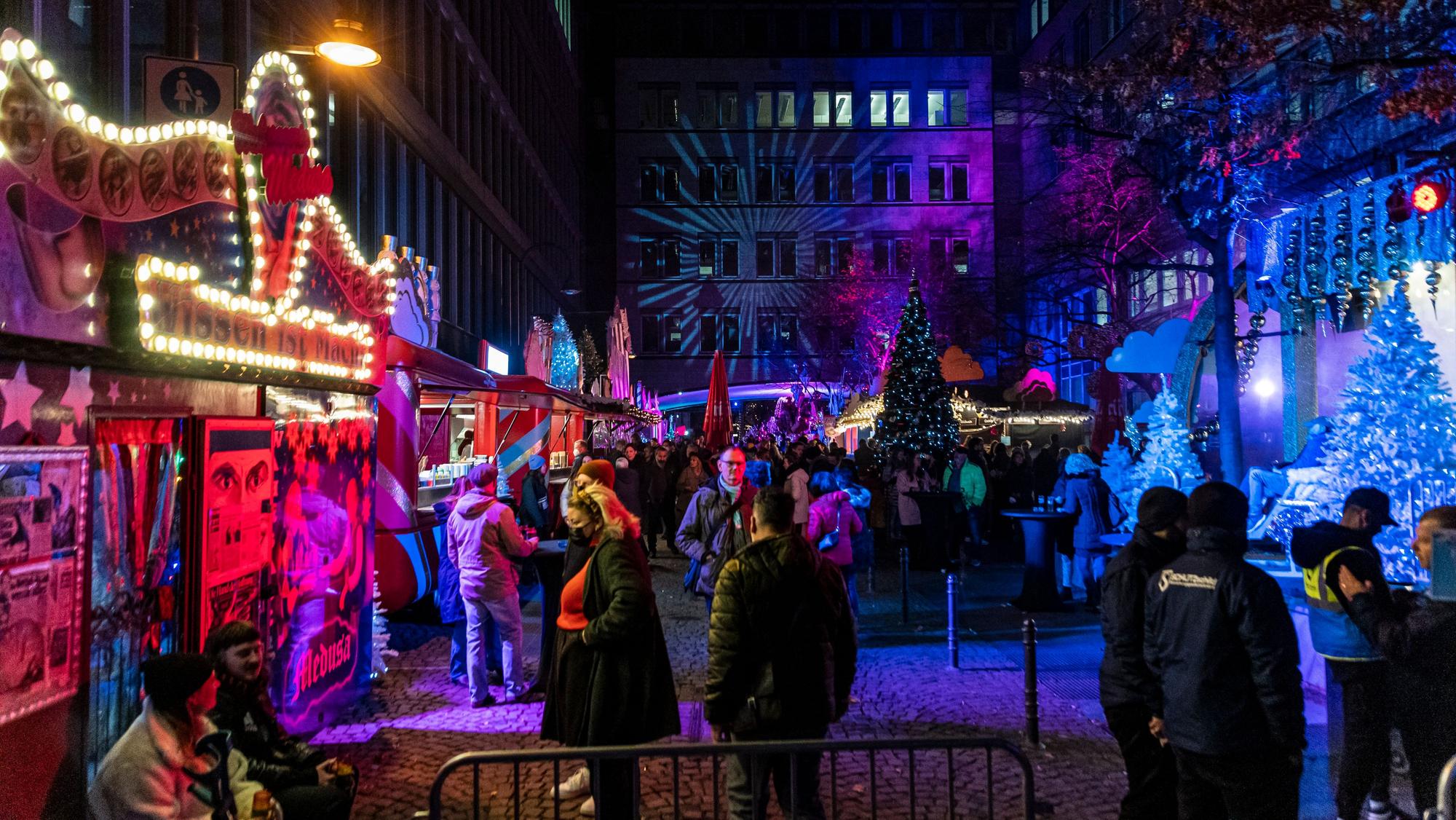 Besucher und Besucherinnen schlendern über den Kölner Weihnachtsmarkt „Heavenue Cologne“.