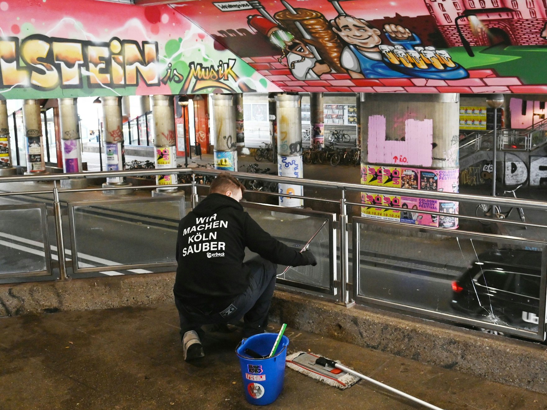 Mitarbeiter einer Reinigungsfirma putzt an der Kölner Haltestelle Hansaring.